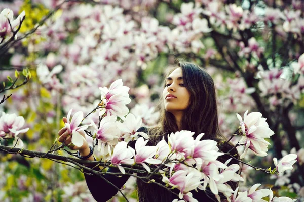 Kobieta z brunetka, długie włosy, pozowanie o drzewa magnolii — Zdjęcie stockowe