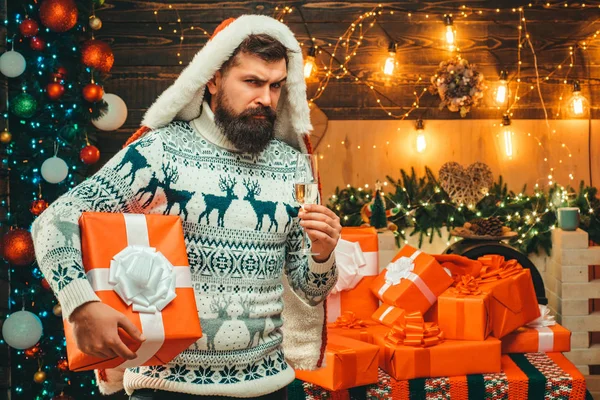 Christmas mannen i santa hatt. Santa Claus gifting gåva. Skäggig moderna Jultomten i stickad tröja. Santa i hem. — Stockfoto