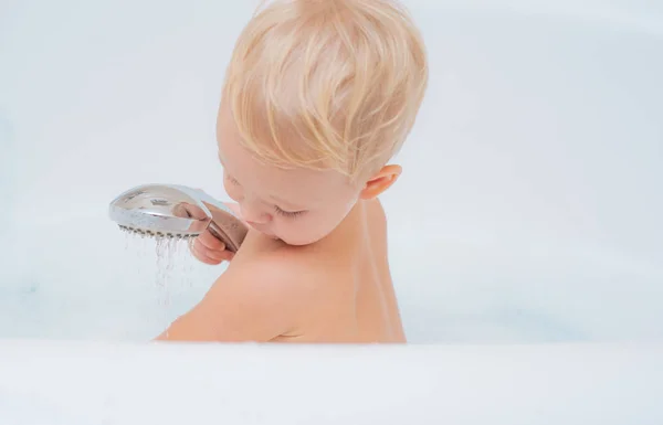 Bebé con una toalla después de tomar un baño. Sonriendo hermoso bebé bañándose bajo una ducha en casa. Jabón de baño infantil . —  Fotos de Stock