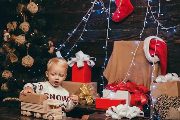 Criança feliz vestida com roupas de inverno pense no Papai Noel perto da árvore de Natal. Feliz Natal e Feliz Ano Novo. Na manhã anterior ao Natal . — Fotografia de Stock