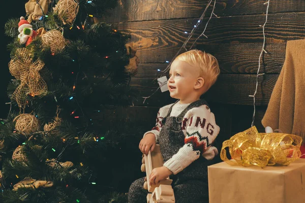 Lustiges Kind mit Weihnachtsgeschenk. Babys. Frohe Weihnachten und frohe Feiertage. Christbaumschmuck. Kindergeschenk. fröhliches süßes Kind, das ein Weihnachtsgeschenk öffnet. Winterkinder. — Stockfoto