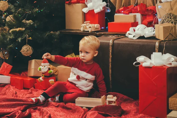 Милый маленький ребенок возле рождественской елки. Рождественские дети. Концепция рождественской истории. Забавный ребенок держит рождественский подарок. Новогодние дети . — стоковое фото