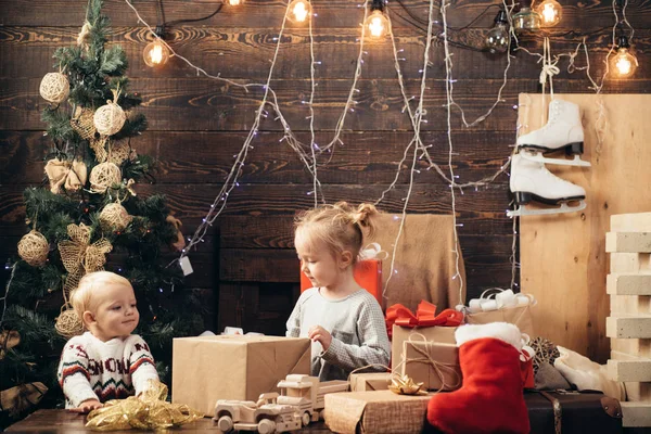 幸せなプレゼントとサンタ帽子で小さい子供がクリスマスを持っています。冬の夜は家で。クリスマスと新年のギフトを開きます。陽気なクリスマスと幸福な新しい年。子供のクリスマス. — ストック写真