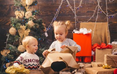 Çocuk kapalı Noel ağacı yakınındaki eğleniyor. Mutlu bir Noel hediye ile Noel Baba şapkalı küçük çocuk sahibi. Mutlu Noeller ve mutlu tatiller. Çocuk hediye. Kış akşam evde.