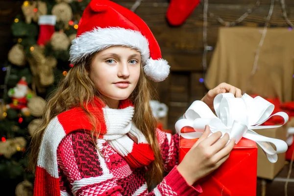 Adolescente presente de Natal. Conceito de história de Natal. Filhos felizes. Abrindo presentes no Natal e Ano Novo. Sorrindo menina espreitando atrás da árvore de Natal na sala de estar . — Fotografia de Stock