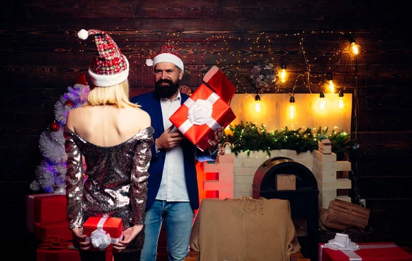 Famiglia di anno nuovo con regalo di Natale davanti all'albero di Natale. Tendenze natalizie moderne. Bello hipster barbuto Babbo Natale con sorridente giovane donna positiva. Amore. . — Foto Stock