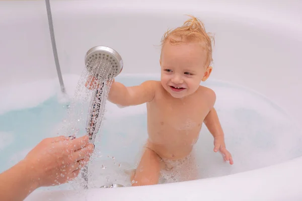 Joyeux visage de bébé dans le bain moussant. Hygiène des enfants. Adorable bébé avec des mousses de savon sur les cheveux prenant un bain . — Photo