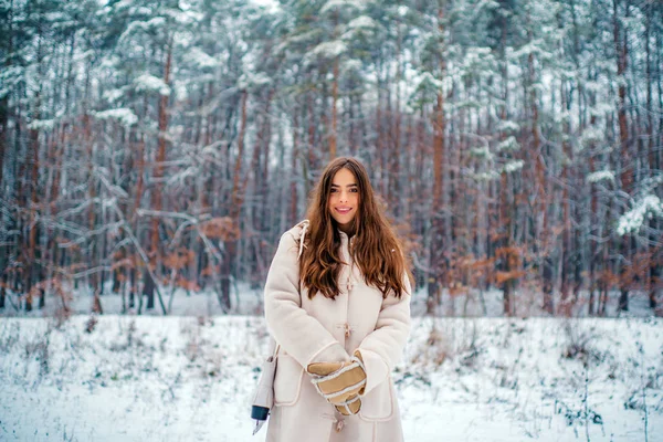 Porträt einer jungen Frau im Schnee, die versucht, sich zu wärmen. Fröhliche Schönheit junge Frau hat Spaß im Winterpark. — Stockfoto