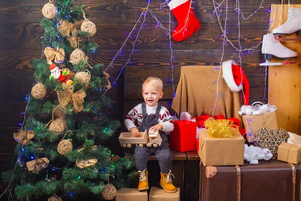 Winterabend zu Hause. glückliches Kind mit einem Weihnachtsgeschenk auf Holzuntergrund. Frohe Weihnachten und frohe Feiertage. Weihnachtskinder. Konzept für Weihnachtsgeschichte. — Stockfoto