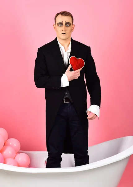 Blissfully in love pantomime. Mime actor has valentines celebration party. Comedian actor hold red heart in bath. Mime man celebrate valentines day. Happy valentines day. Love confession