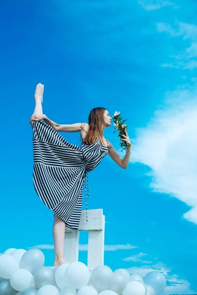 Portret van de mode voor de vrouw. meisje met bloemen zitten in de hemel. gevoel vrijheid en dromen. inspiratie en verbeelding. vrouw in de zomer jurk met ballonnen van de partij. acrobatiek en sport. spli — Stockfoto