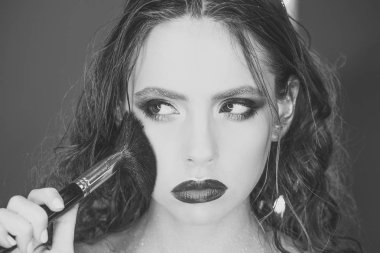 Güzellik kız makyaj fırça ile. Kahverengi gözlü esmer kadın için parlak tatil makyaj. Güzel yüz ve makyaj. Mükemmel cilt. Makyaj uygulamak