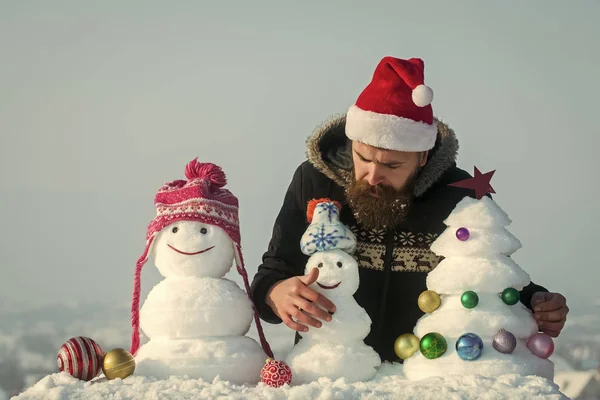 Сніговики в капелюхах і снігова ялинка на блакитному небі — стокове фото