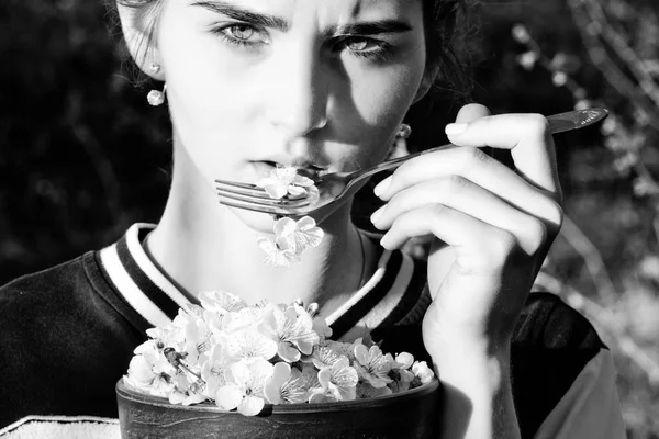 Cute girl eating cherry blossom petals with metallic fork — Stock Photo, Image