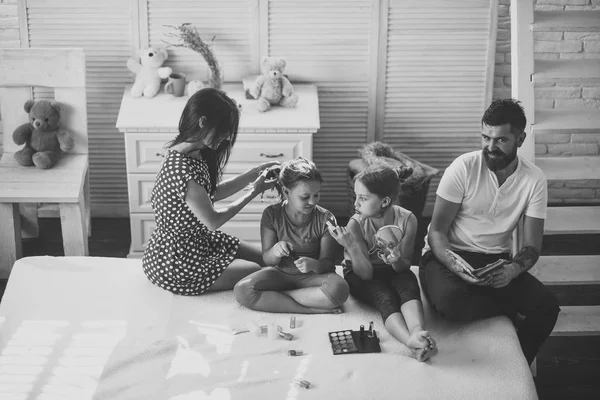 Vader leest, moeder maakt dochter kapsel, meisjes doen make-up — Stockfoto