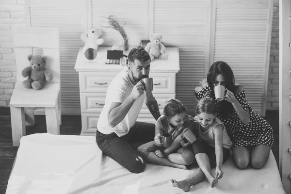 Mother, father and daughters with tea cups in apartment