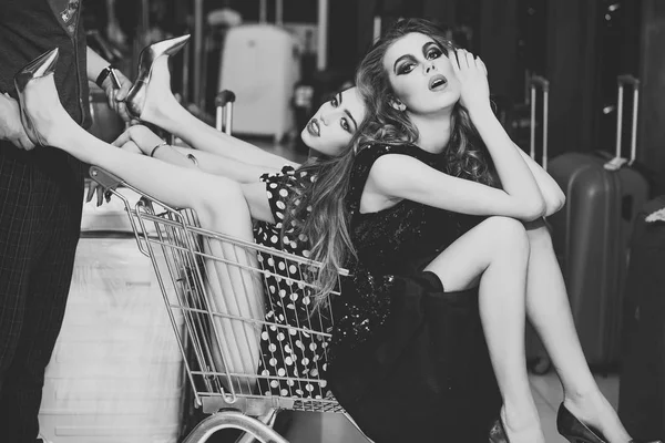 Women shoppers sit in shopping cart, trolley — Stock Photo, Image