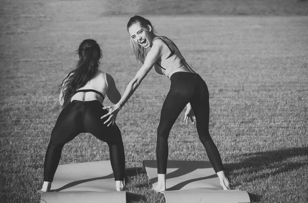 Energy women do athletic exercises on green grass