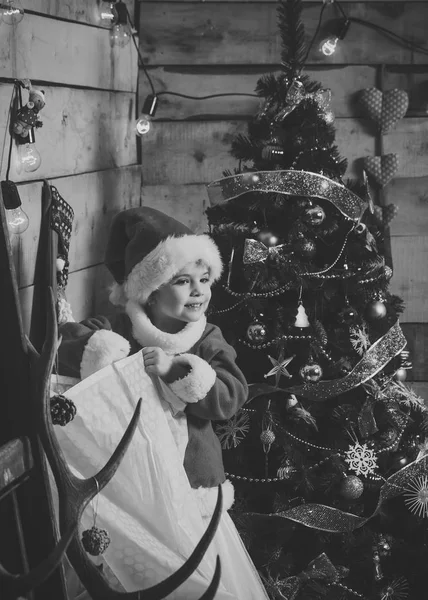 Weihnachtsfeier. Winterurlaub und Urlaub. Neujahr kleines Mädchen mit Hut. Weihnachtsglückliches Kind mit Weihnachtsmann am Weihnachtsbaum. — Stockfoto