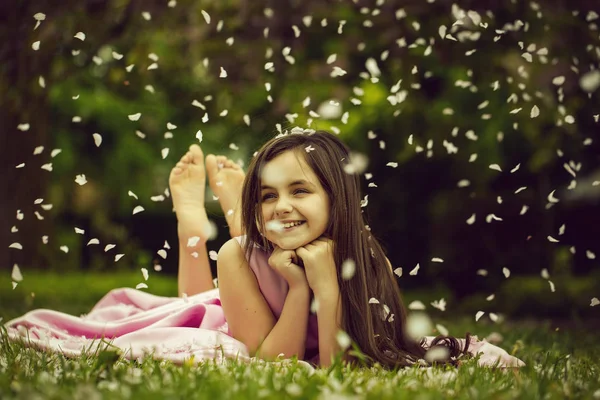 Niña sobre hierba verde con pétalos — Foto de Stock