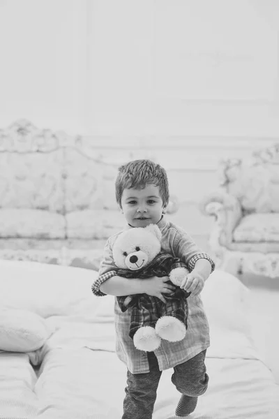 Boy with happy face holds favourite toy fluffy bear. Child with soft teddy bear in hands. Kid play with plush bear, luxury interior background. Happy childhood concept. Little cute toddler carries toy — Stock Photo, Image