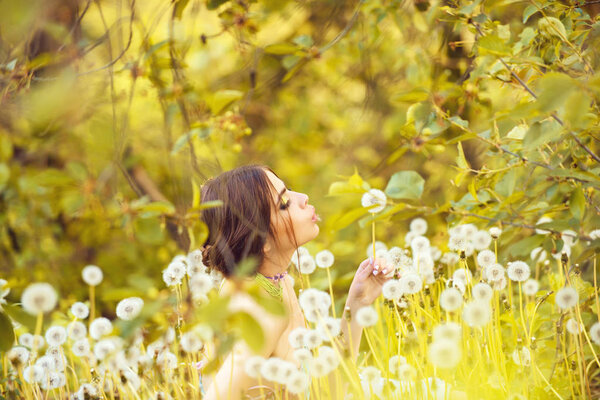 Woman. girl with fashionable makeup and beads in green leaves and dandelion flower on natural background, beauty and fashion, youth and freshness