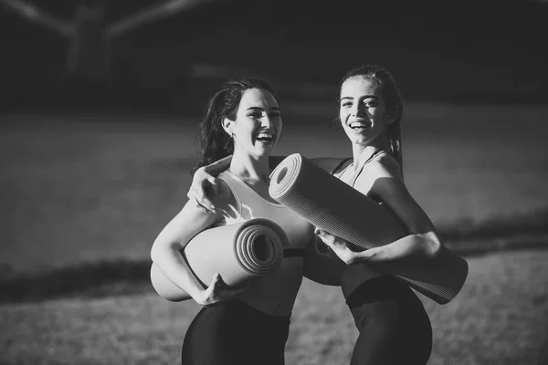Hermosas mujeres sonríen con colchonetas de yoga — Foto de Stock