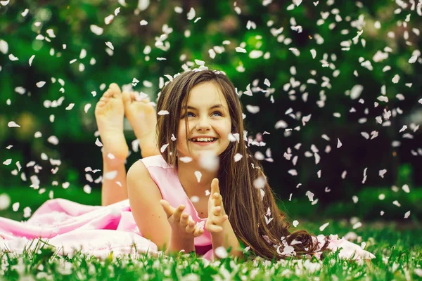 Μικρό κορίτσι για την πράσινη χλόη με πέταλα — Φωτογραφία Αρχείου
