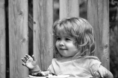 küçük çocuk ahşap çit yakınındaki pasta yemek