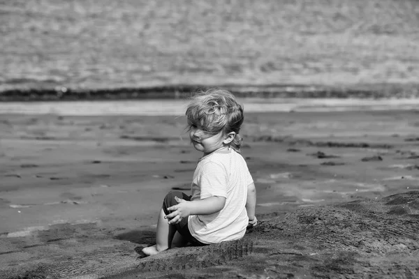 Lindo bebé niño se sienta en la arena en la playa de arena — Foto de Stock