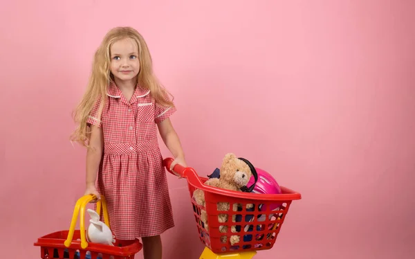 Parece retrô. Pequeno comprador. Uma menina a fazer compras. Pequena shopaholic com carrinho de compras. Menina pequena na loja. Vai às compras, copia espaço — Fotografia de Stock