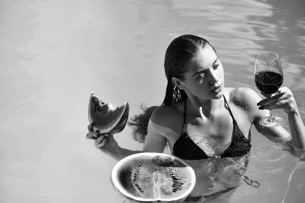 Женщина с арбузом и вином в бассейне — стоковое фото