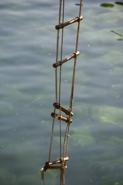 Başarıya ulaşmak. İp merdiven. Jacobs merdiven. İp merdiven ahşap adımlarla. İp su yüzeyi üzerinden. Kurtarma veya kaçış ip. .Başarı merdivenini hızla tırmanıyorum. Hırs yüksekliğini