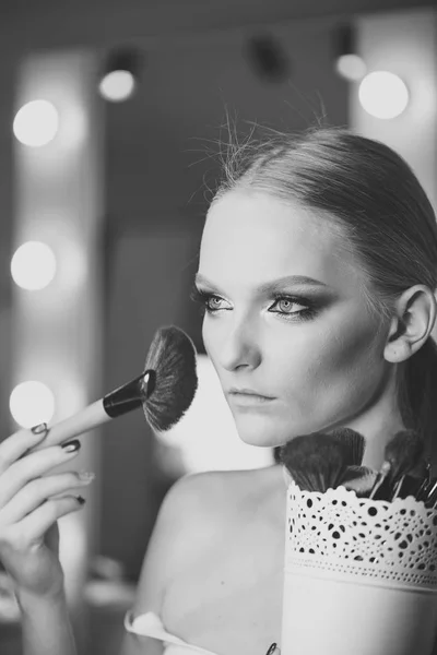 Hermosa mujer joven aplicando polvo de fundación o rubor con cepillo de maquillaje — Foto de Stock