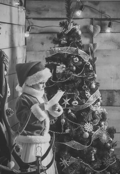 Weihnachtsmädchen in roter Weihnachtsmütze liest Wunschbrief — Stockfoto