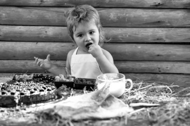 Tatlı küçük çocuk böğürtlen yiyor.