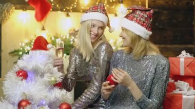 Yeni yıl şapka gülümseyen kız şampanya içmek ve bir Noel ağacı süsleyin. Kızlar bir Noel ağacı süsleyin. Yeni yıl ruh hali. Yeni yıl ve Noel