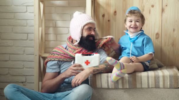 Kleine jongen gekleed in een arts speelt met zijn vader. Jonge dokter. Vader en zoon spelen kliniek thuis. — Stockvideo
