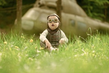 Çocuk pilot kask ve yeşil çim oturan gözlük