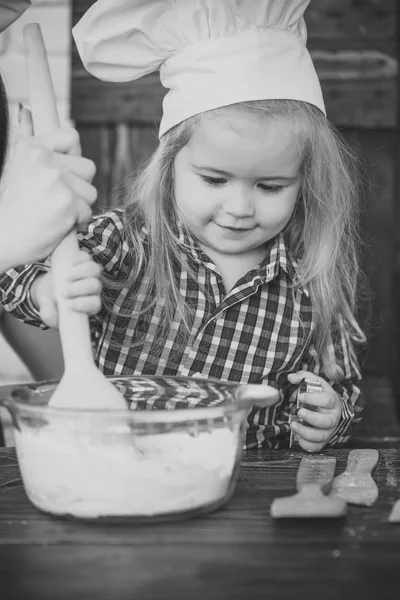 Bambino in cappello da chef mescolando pasta con cucchiaio di legno — Foto Stock