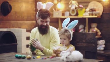 Baba ve oğul Paskalya yumurtaları renk. Sevimli küçük çocuk çocuk Bunny kulaklar giyiyor. Paskalya yumurtaları ahşap arka plan üzerinde. Mutlu Paskalya.