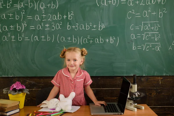 Los alumnos de la escuela utilizan la computadora portátil para acceder a la educación en línea en el aula. Niña tienen lección en el cuaderno para los estudiantes a distancia durante la educación en línea — Foto de Stock