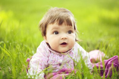 Yeşil çimenlerin üzerinde şirin bebek kız