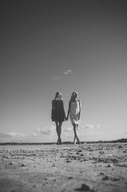 İkizler yaz aylarında mavi gökyüzü arka plan üzerinde yürümek.