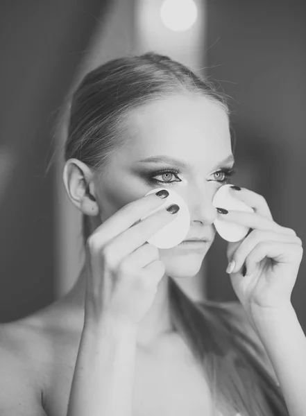 Mirada de mujer bonita maquillaje correcto. Mira, la mujer usa algodón para limpiar la piel de la cara . — Foto de Stock