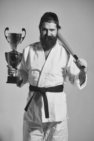 Bearded karate man in kimono, green baseball bat, champion cup — Stock Photo, Image