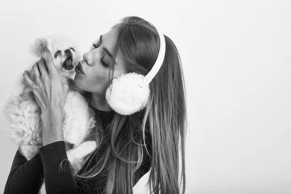 Sexy bonita chica besos pequeño pomeranian perro en orejeras — Foto de Stock