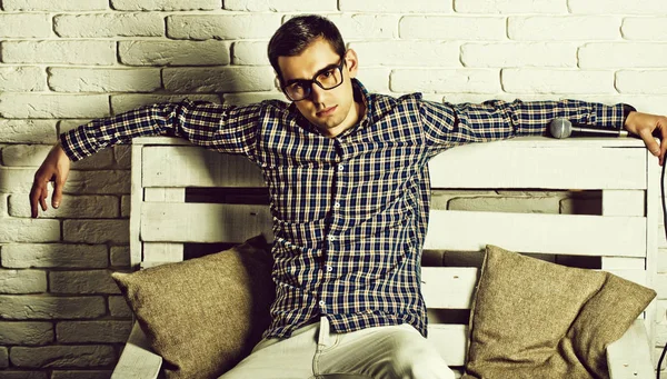 Chlápek v brýlích a kostkovanou košili na lavici s mikrofonem — Stock fotografie