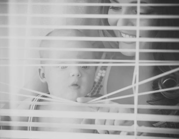 Kvinna med barn smile på fönsterluckor — Stockfoto