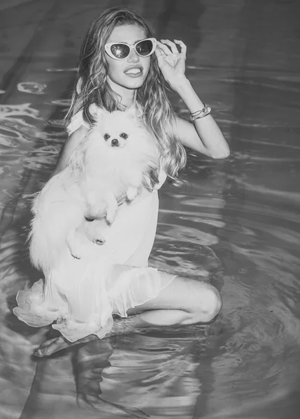 Girl with small dog in swimming pool